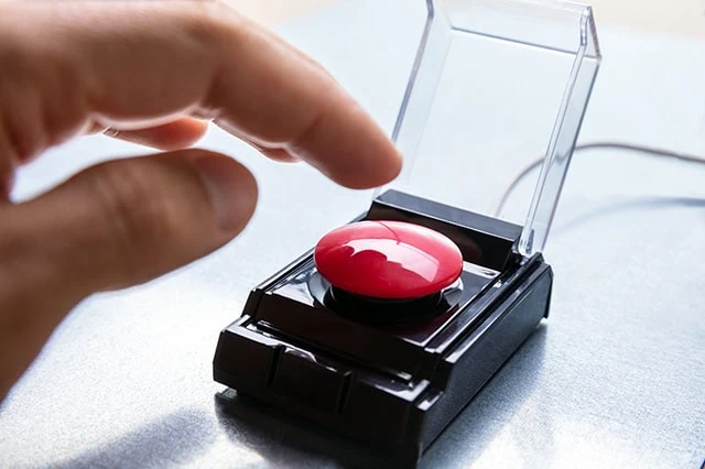a finger goes to press a small panic button.