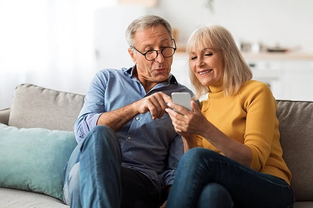 a happy older couple looking at a smartphone.